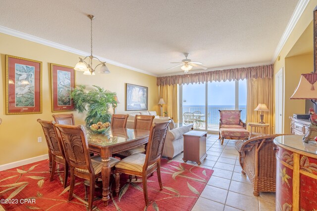 tiled dining space featuring a textured ceiling, ceiling fan with notable chandelier, ornamental molding, and a water view