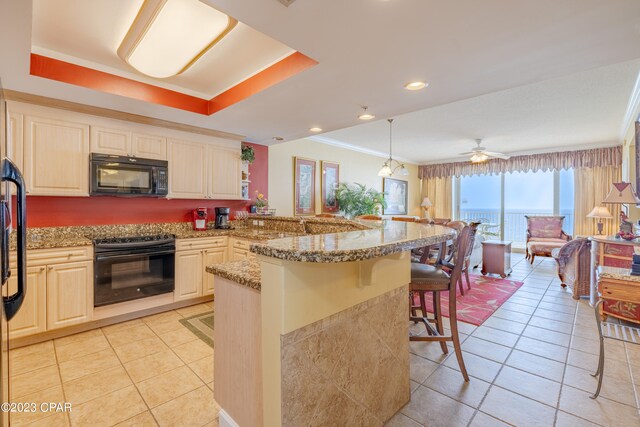 kitchen featuring ceiling fan, pendant lighting, kitchen peninsula, black appliances, and a breakfast bar area