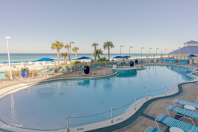 view of pool featuring a water view, a community hot tub, and a patio area