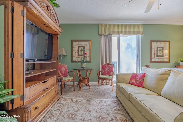 living room featuring ceiling fan, a textured ceiling, light carpet, and ornamental molding