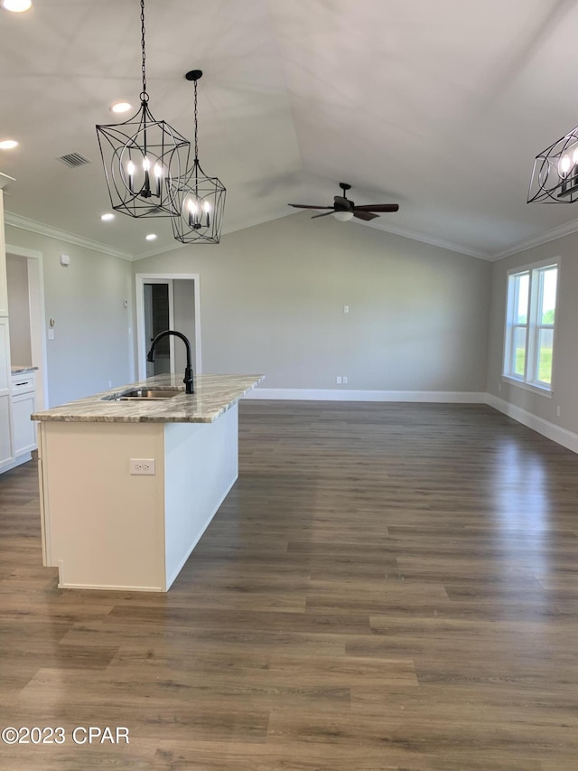 kitchen featuring decorative light fixtures, vaulted ceiling, white cabinetry, and a center island with sink