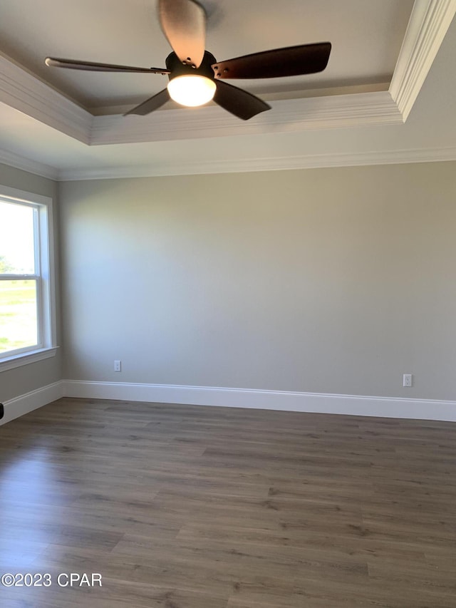 spare room featuring dark wood-type flooring, ornamental molding, a tray ceiling, and ceiling fan