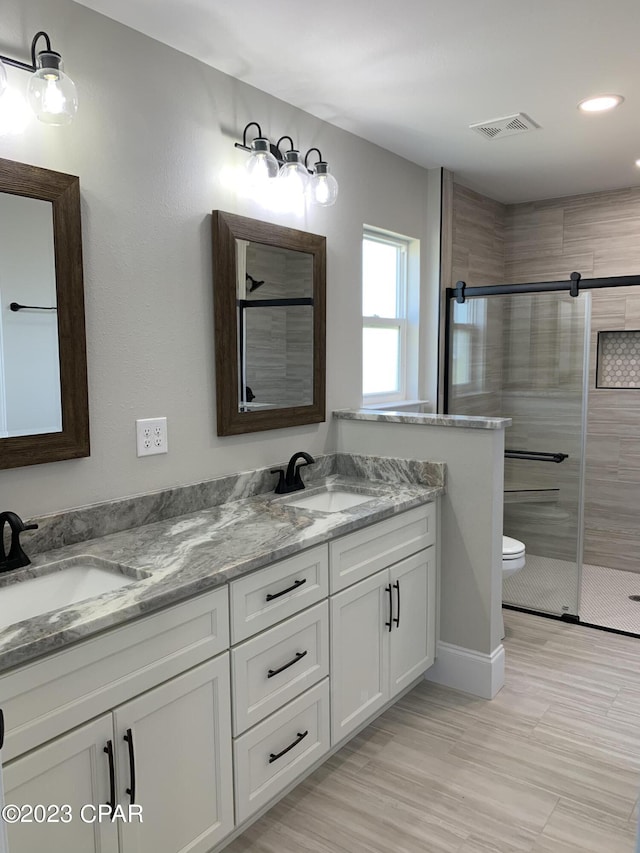 bathroom with vanity, toilet, and a shower with door