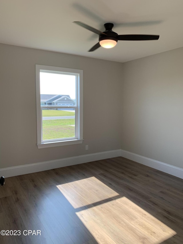 empty room with ceiling fan and dark hardwood / wood-style flooring