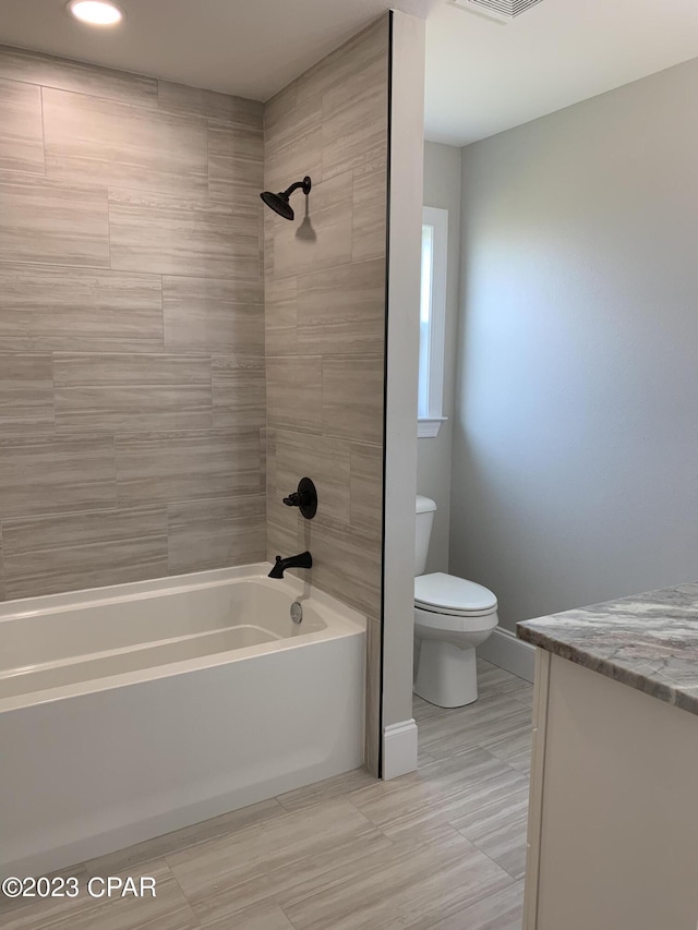 full bathroom featuring toilet, tiled shower / bath, and vanity