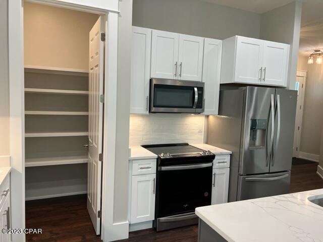 kitchen featuring appliances with stainless steel finishes, decorative backsplash, white cabinetry, and dark wood-type flooring