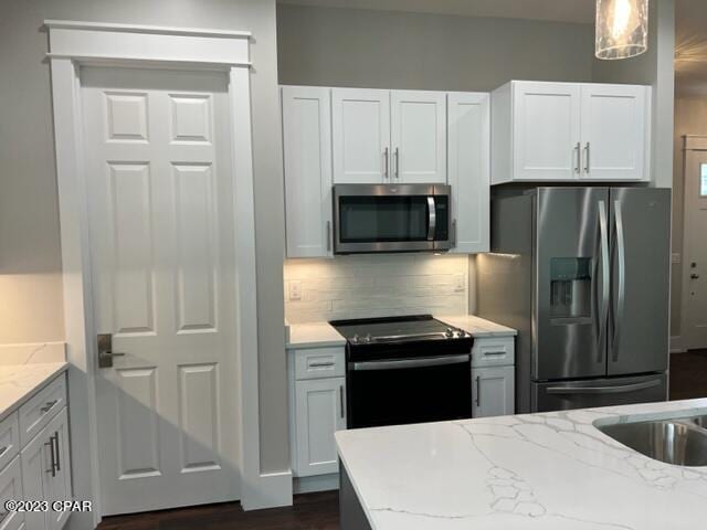 kitchen with hanging light fixtures, white cabinetry, and stainless steel appliances