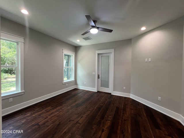 unfurnished room featuring a wealth of natural light, ceiling fan, and dark wood-type flooring