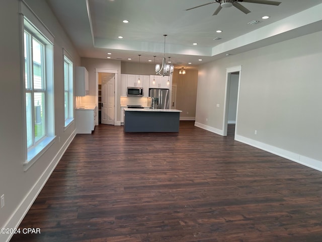 kitchen featuring appliances with stainless steel finishes, ceiling fan with notable chandelier, dark wood-type flooring, and pendant lighting