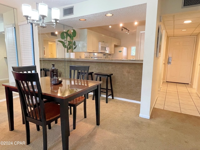 dining room with light carpet, a textured ceiling, and an inviting chandelier