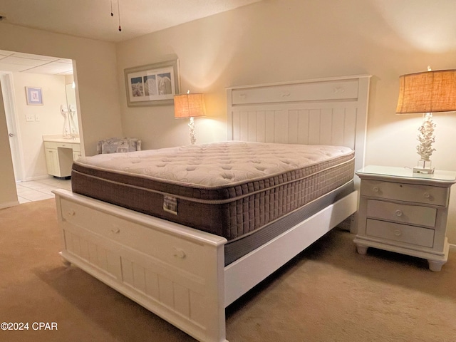 bedroom featuring connected bathroom and light carpet