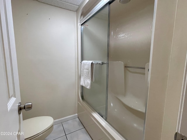 bathroom featuring combined bath / shower with glass door, toilet, and tile patterned floors