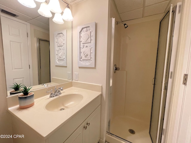 bathroom with a drop ceiling, vanity, and a shower with shower door