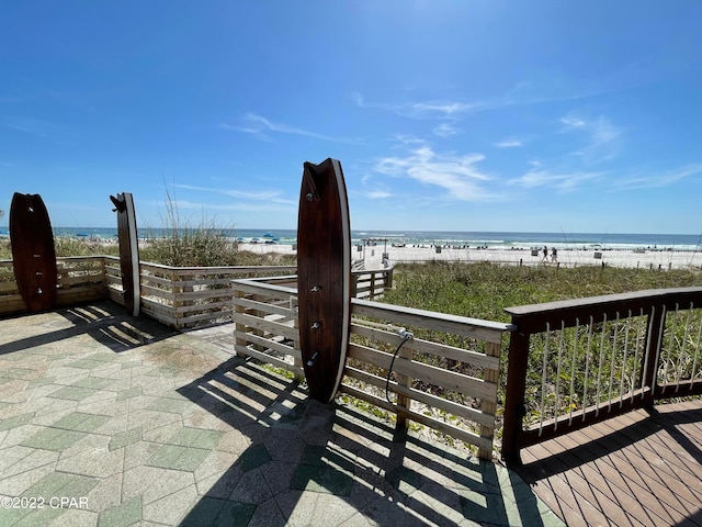 view of patio with a water view and a beach view