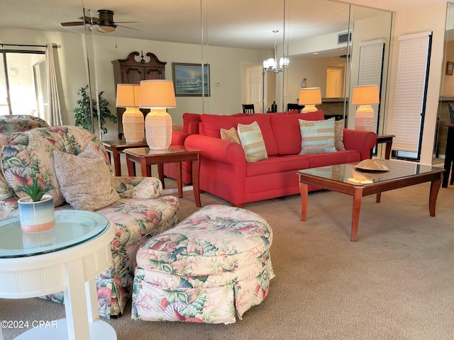 living room featuring light carpet and ceiling fan with notable chandelier