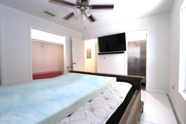 tiled bedroom featuring ceiling fan, a walk in closet, and a closet