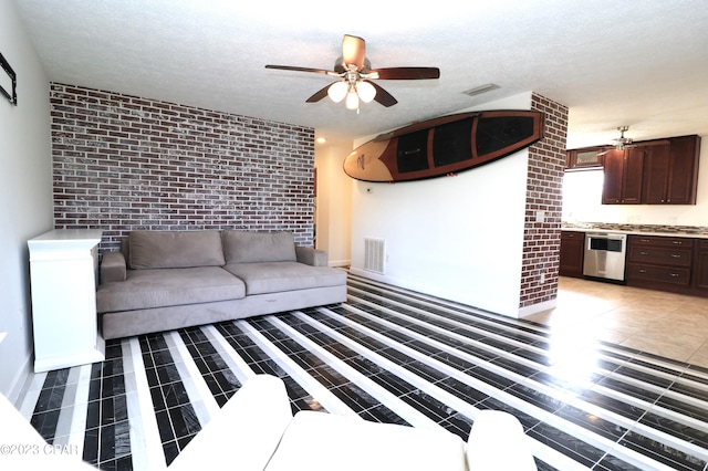 unfurnished living room with ceiling fan, brick wall, and a textured ceiling