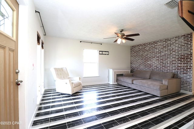 unfurnished living room featuring ceiling fan, a textured ceiling, and brick wall