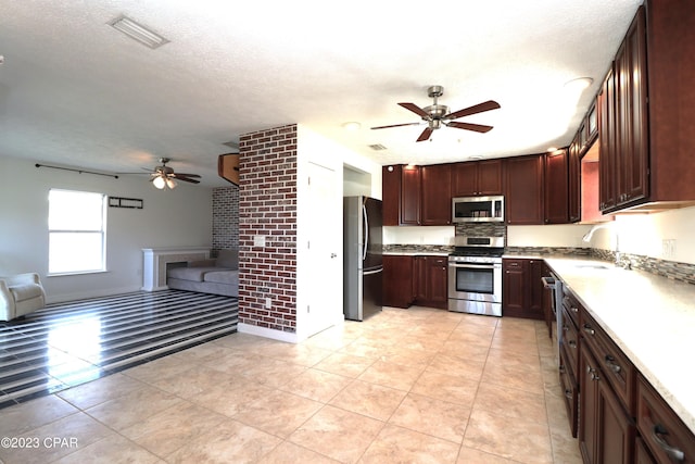 kitchen featuring light tile patterned flooring, stainless steel appliances, a textured ceiling, ceiling fan, and sink