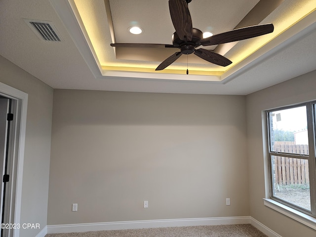 empty room featuring carpet, ceiling fan, and a tray ceiling