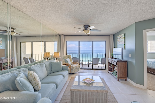 tiled living room featuring a textured ceiling, ceiling fan, and a water view