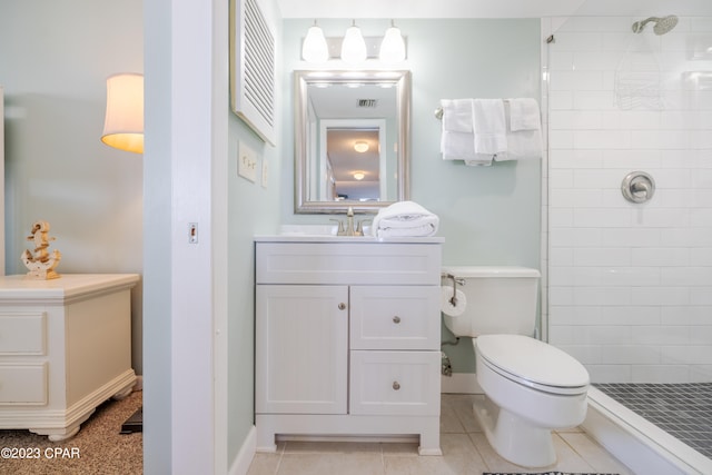 bathroom featuring toilet, tile floors, vanity, and tiled shower