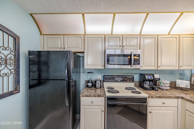 kitchen featuring black refrigerator and white range with electric cooktop