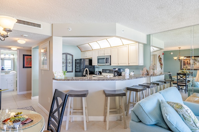 kitchen featuring kitchen peninsula, black refrigerator, light tile flooring, a textured ceiling, and a notable chandelier