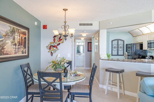 dining area with light tile floors, a textured ceiling, and an inviting chandelier