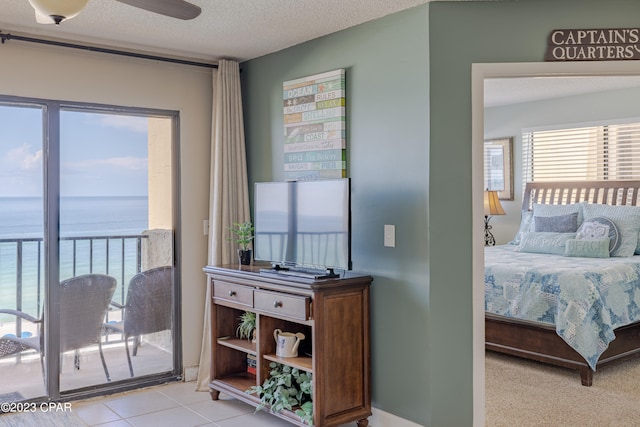 bedroom featuring light tile floors, ceiling fan, a textured ceiling, a water view, and access to outside