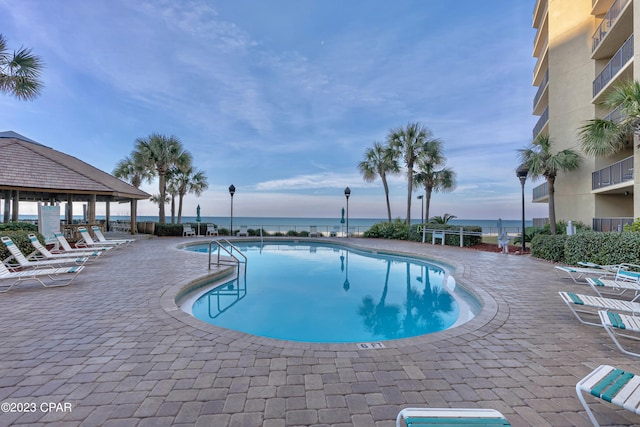 view of swimming pool featuring a water view and a patio area