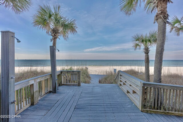 wooden deck with a water view and a view of the beach