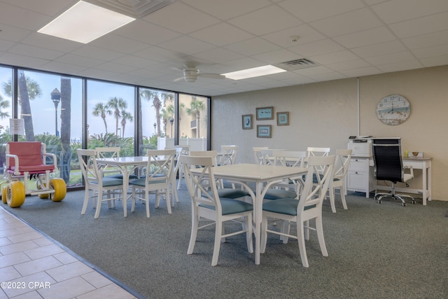 tiled dining space with a drop ceiling, ceiling fan, and a wealth of natural light