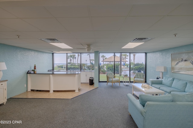 carpeted living room featuring floor to ceiling windows and a paneled ceiling