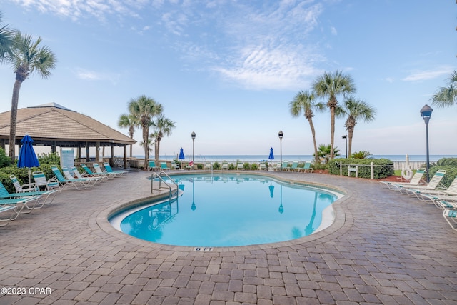 view of pool with a gazebo, a water view, and a patio