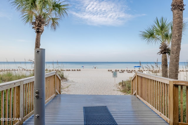 wooden terrace featuring a water view and a beach view