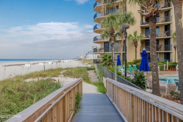 surrounding community with a beach view, a swimming pool, and a water view