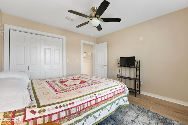 bedroom with light hardwood / wood-style flooring, ceiling fan, and a closet