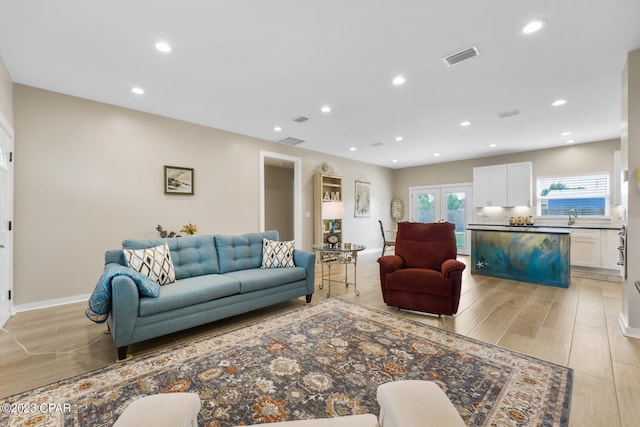 living room featuring french doors, sink, and light hardwood / wood-style floors