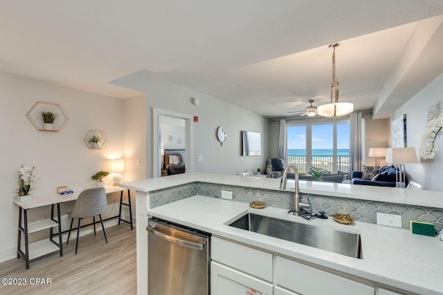 kitchen with light wood-type flooring, a water view, dishwasher, sink, and white cabinets