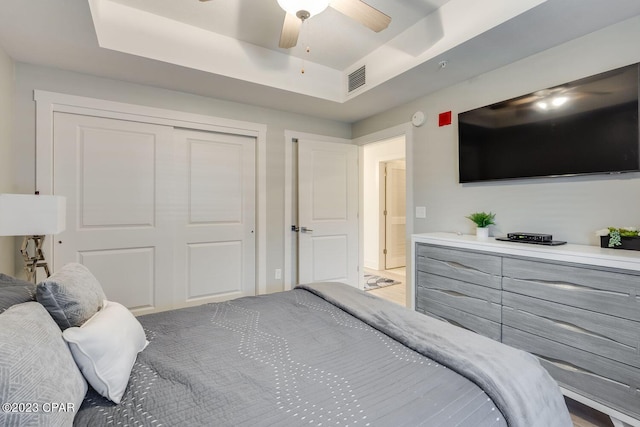 bedroom featuring ceiling fan, a closet, and a tray ceiling