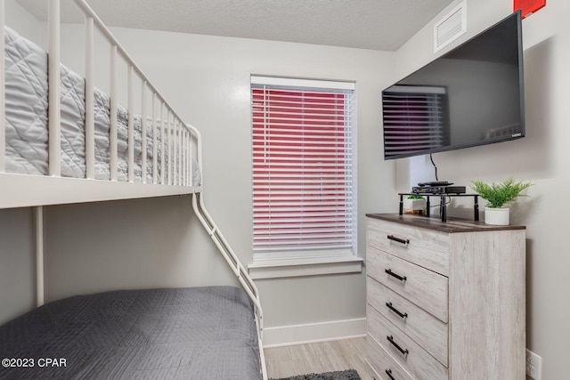 bedroom featuring light hardwood / wood-style floors and a textured ceiling