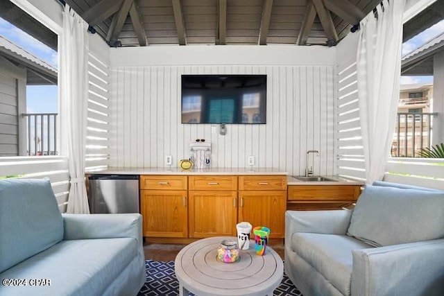 bar featuring sink, stainless steel fridge, wooden walls, and lofted ceiling with beams