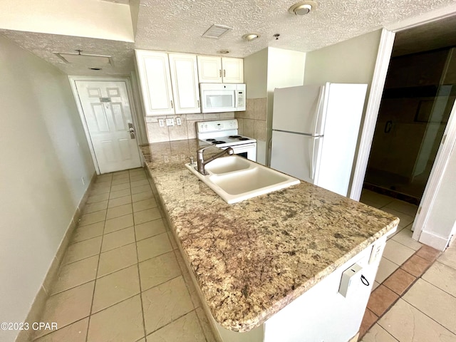 kitchen with backsplash, light tile flooring, white appliances, sink, and white cabinets