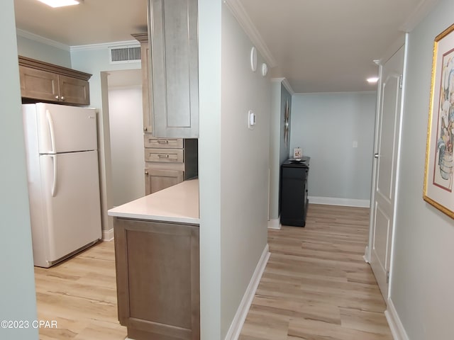 hallway with light wood-style floors, visible vents, crown molding, and baseboards