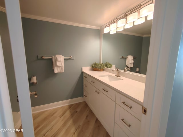 bathroom featuring crown molding, toilet, vanity, wood finished floors, and baseboards