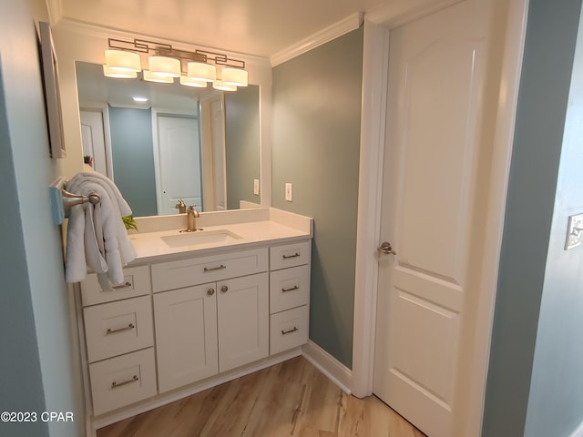 bathroom with ornamental molding, vanity, baseboards, and wood finished floors