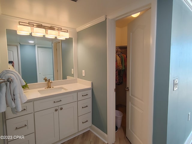 bathroom with toilet, vanity, baseboards, ornamental molding, and a walk in closet