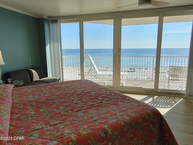 bedroom with access to exterior, a water view, crown molding, and wood finished floors