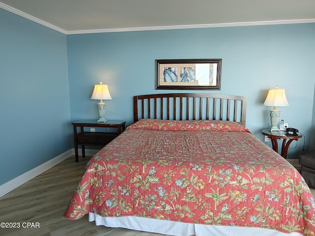 bedroom with baseboards, crown molding, and wood finished floors